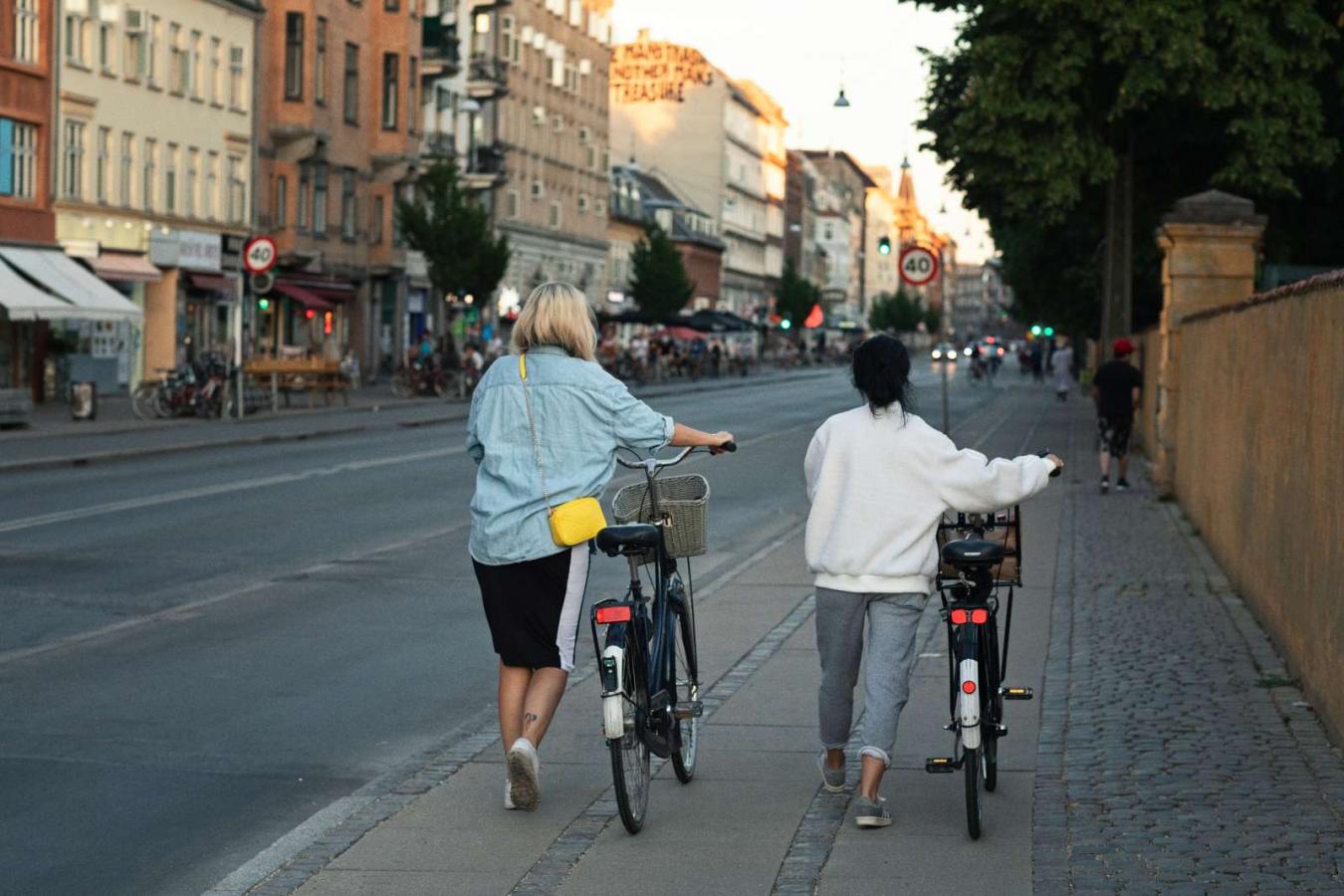 Girls walking down Nørrebrogade with their bikes.
