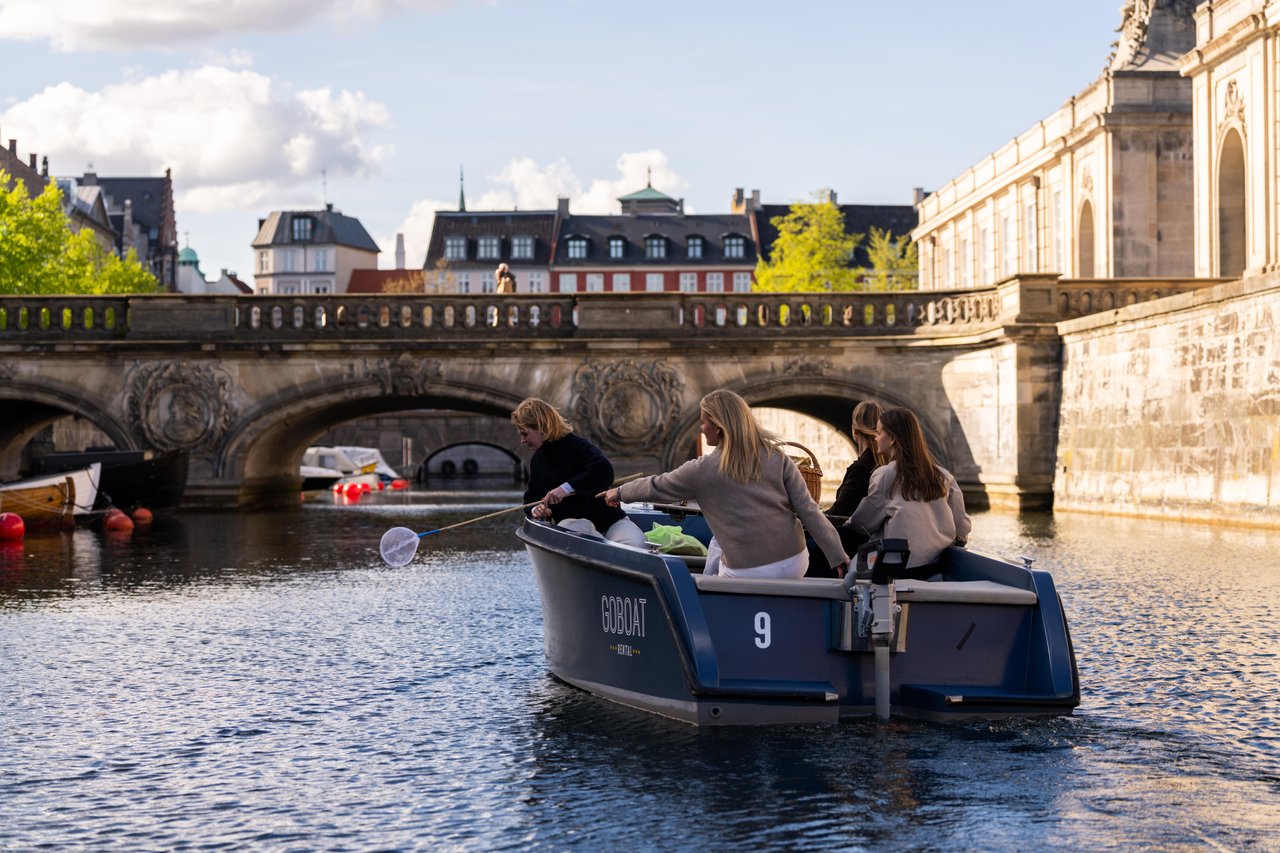 People collecting litter from the water in a small electric boat on Frederiksholms Kanal in Copenhagen as part of the CopenPay initiative.